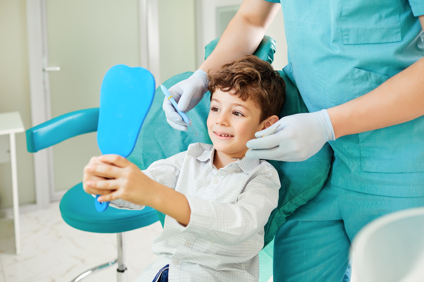 Enfant souriant avec un miroir chez le dentiste 